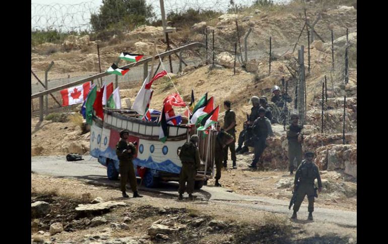 • Palestinos protestan con una representación de la Flotilla de la Libertad, en la valla entre Israel y Cisjordania. REUTERS  /