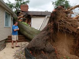 Un hombre observa su casa destruida por un arbol, a causa de un tornado. AP  /