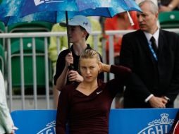 María Sharapova, bajo una sombrilla tras la suspención por la lluvia. AP  /