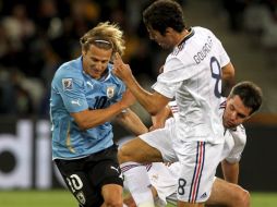 Diego Forlán intenta evadir la marca de Yohan Gourcoff. EFE  /