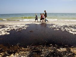 Una familia esquiva una mancha de petróleo, producto del derrame en el Golfo de México. EFE  /