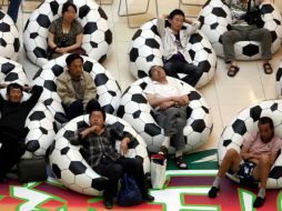 Residentes de China descansan entre dos partidos de futbol de la Copa en Sudáfrica. Mientras, su nación espera crecer 10% este año. AP  /