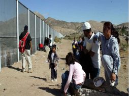 Una familia de migrantes se encuentran en el muro fronterizo. ESPECIAL  /