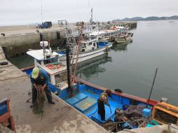 Dos hombres limpian un barco pesquero en un puerto de la isla de Baengnyeong, Corea del Sur. EFE  /