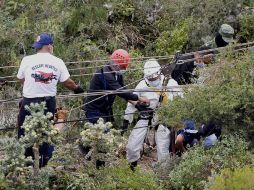 Forenses acompañados por soldados y policías realizan el levantamiento de tres cuerpos hallados en el acceso de una mina. EFE  /