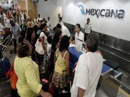 Clientes se formaban frente al mostrador exigiendo a los aún empleados de Mexicana que les dieran una solución. REUTERS  /