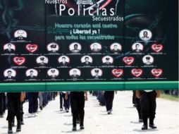 Un cartel con los retratos y los nombres de policías secuestrados es exhibida durante una marcha contra el secuestro. EFE  /