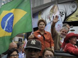 Dilma Rousseff avanza entre la multitud con bandera en mano. A un lado, el presidente Lula. AFP  /