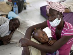 Una mujer carga a su hija mientras espera ser atendida en un hospital de Haití tras el brote de cólera. AFP  /
