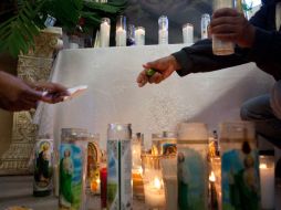Familiares de víctimas de la masacre prenden veladoras durante su funeral. AFP  /