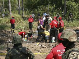 Peritos forenses trabajan este miércoles en la fosa clandestina, resguardados por militares. AFP  /