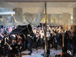 Jóvenes arrojan una silla contra los ventanales de la sede del Partido Conservador. EFE  /