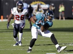 Mike Thomas corre con el balón y evita el ataque de Eugene Wilson de Houston. AP  /