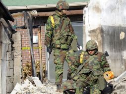 Varios soldados surcoreanos revisan una zona destruida por los misiles de Corea del Norte, en la isla de Yeonpyeong. AFP  /