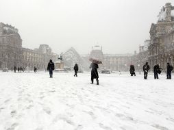 Parisinos disfrutan la nieve al circular por la plaza en la que se erige el Museo del Louvre. AFP  /