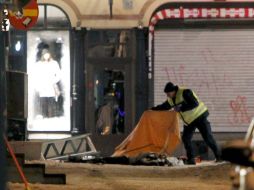 Un policía tapa con una manta al cadáver fallecido. EFE  /