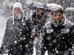Londinenses pasan por el centro de Londres, Inglaterra, bajo una intensa nevada. EFE  /