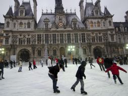 Niños y adultos disfrutan del patinaje sobre hielo en una pista montada frente al ayuntamiento de París. EFE  /