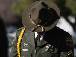 Un polcía vestido con el uniforme de gala inclina la cabeza ante el paso del cortejo fúnebre de un compañero. AP  /