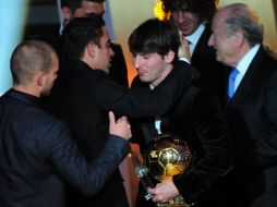 Xavi Hernández y Andrés Iniesta felicitando a Messi tras recibir el trofeo. AFP  /