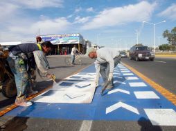 Trabajadores dan los últimos toques a la señalización de la ciclovía ubicada sobre Periférico. A. GARCÍA  /