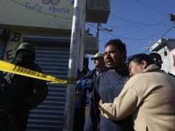 Dos personas lloran la muerte de sus familiares,  y un marino resguarda la zona del ataque, ocurrido al oriente de Monterrey. REUTERS  /