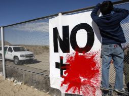 Un joven coloca una bandera con la leyenda ''No más sangre'' en la  valla fronteriza que separa México  y EU en Ciudad Juárez. REUTERS  /