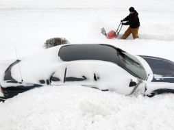 Un hombre limpia la nieve de su jardín, la nevada fue tan intensa que varios autos quedaron atrapados. AP  /