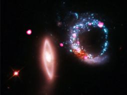 El telescopio espacial Hubble captó imágenes en rojo, verde y azul de una galaxia espiral azul con pequeños puntos rosas. ESPECIAL  /