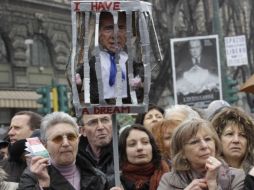 Un grupo de  mujeres tienen un cartel  con una foto de, Silvio Berlusconi, tras las rejas durante una protesta en Milán, Italia. AP  /