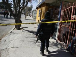 Un agente federal vigila la zona donde cuatro jóvenes fueron asesinados en un taller. EFE  /