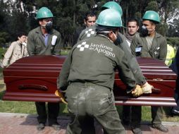 Empleados del cementerio cargan el ataúd de 'Mono Jojoy' durante en entierro. REUTERS  /