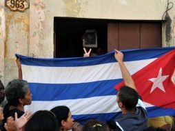 Partidarios del Gobierno cubano colocan una bandera del país en una casa a manera de protesta. EFE  /