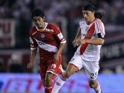 Darío Ocampo, de Argentinos Juniors, trata de frenar a Matías Almeyda, de River Plate. AFP  /