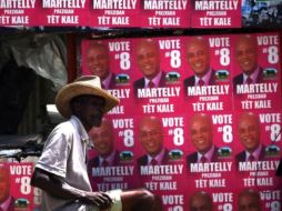 Un  hombre pasa cerca de los carteles de la campaña presidencial en Puerto Príncipe. AFP  /