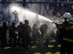 Elementos de seguridad lanzan agua a los aficionados que trataban de ingresar a la cancha. REUTERS  /