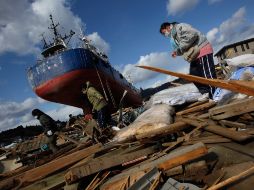 Sobrevivientes del sismo del 11 de marzo buscan hoy sus pertenencias en Kesennuma, en la prefectura de Miyagi. AP  /
