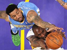 Kobe Bryant va en busca del balón, luchando contra el jugador de los Nuggets, Wilson Chandler. AP  /