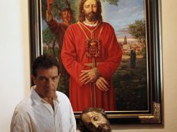 Posa para los fotógrafos cerca de una pintura y la escultura de Cristo que llega para una conferencia de prensa en Málaga. REUTERS  /