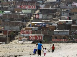 Una mujer y sus hijos caminan hacia las casas con propaganda de la candidata presidencial Keiko Fujimori. REUTERS  /