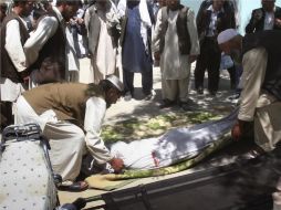 Afganos levantan el cuerpo de un hombre que perdió la vida en el atentado. AP  /