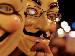 Dos personas con las caretas que lucen los miembros del colectivo Anoymous, entre miles de personas en Madrid. EFE  /