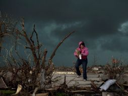Una mujer trata de rescatar medicamentos de su casa tras la destrucción. AFP  /