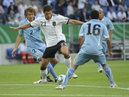 Diego Lugano  y Pereira de Uruguay luchan por el balón con Mario Gómez, quien le daría el primer gol a Alemania. EFE  /