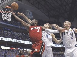 Dwyane Wade se cuela entre la marca de Dirk Nowitzki y Jason Kidd para anotar puntos en la canasta de los Mavericks. REUTERS  /