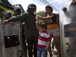 Una familia camina a través de un punto de seguridad de los guardias antimotines de Venezuela, cerca de la prisión El Rodeo I. REUTERS  /