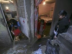 Dos habitantes de Ecatepec sacan a cubetazos el agua que inundó sus viviendas. AP  /