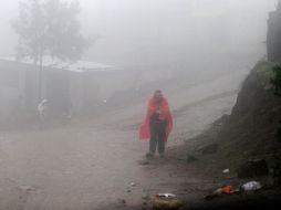Una mujer camina bajo la torrencial lluvia en el poblado evacuado. REUTERS  /