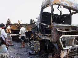 Yemeníes inspeccionan la escena donde quedó el coche incinerado. AFP  /