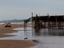 Un vehículo pasa junto a una palapa tras el paso de 'Nate' por la playa Chachalaca, en Veracruz. AP  /